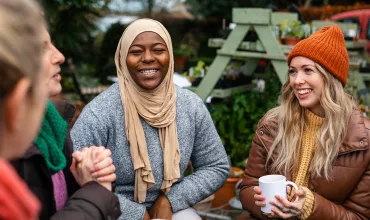Group of warm clothed women, seated outside, smiling and laughing Group of warm clothed women, seated outside, smiling and laughing