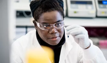 A female research scientist in a lab looking at a sample A female research scientist in a lab looking at a sample