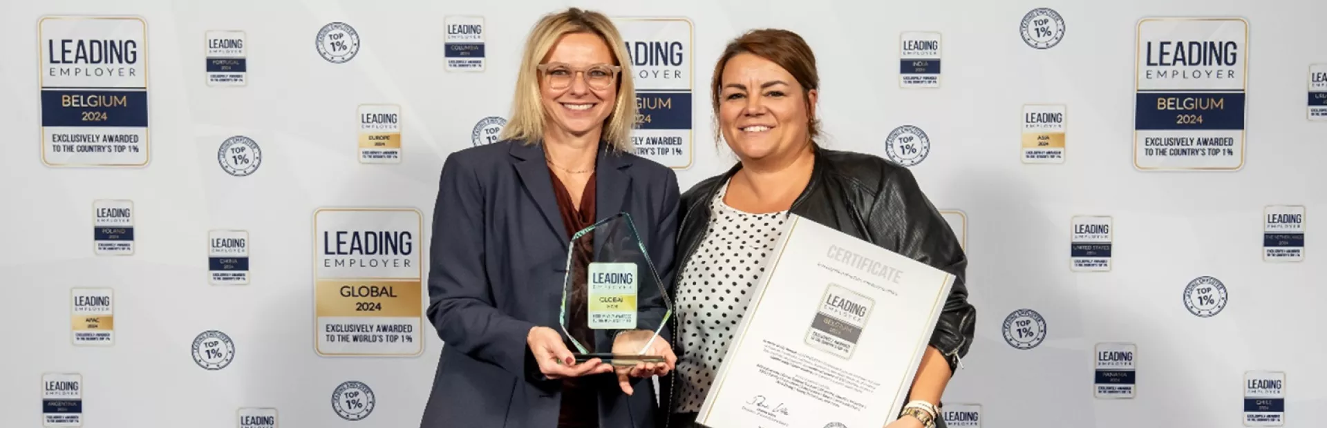 Two smiling persons with the award of Leading Employer 2024