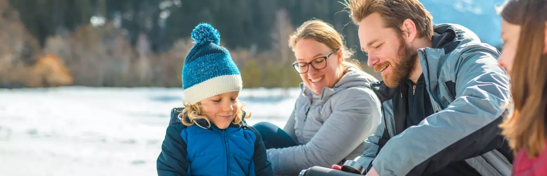 En familj som äter sin matsäck intill en sjö. Foto.