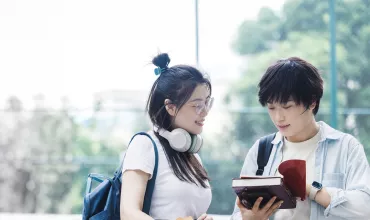 teenagers looking at a book outside