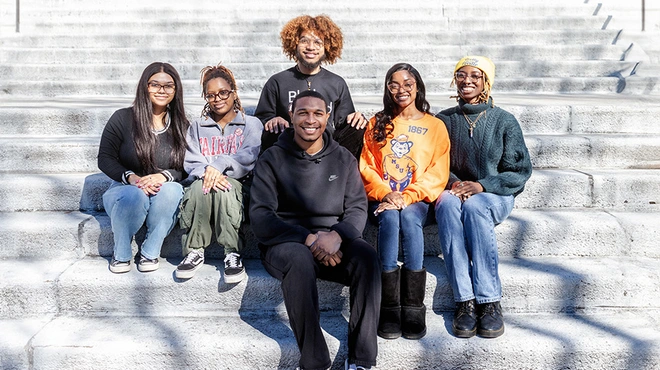 inclusive-health-accelerators-group-photo a group of young people sitting on a stair outside in from of a building