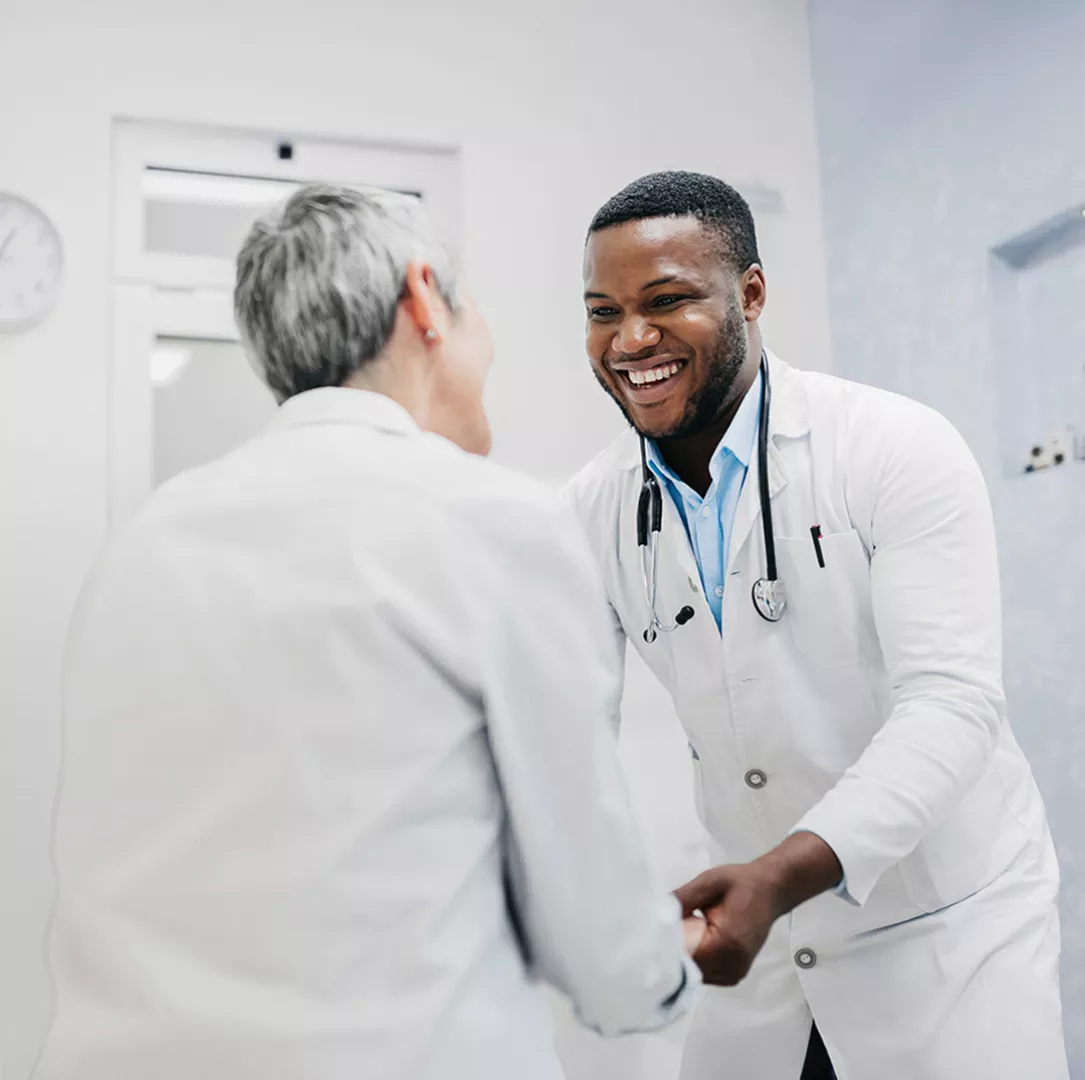 Medical professional and patient smiling and holding hands 